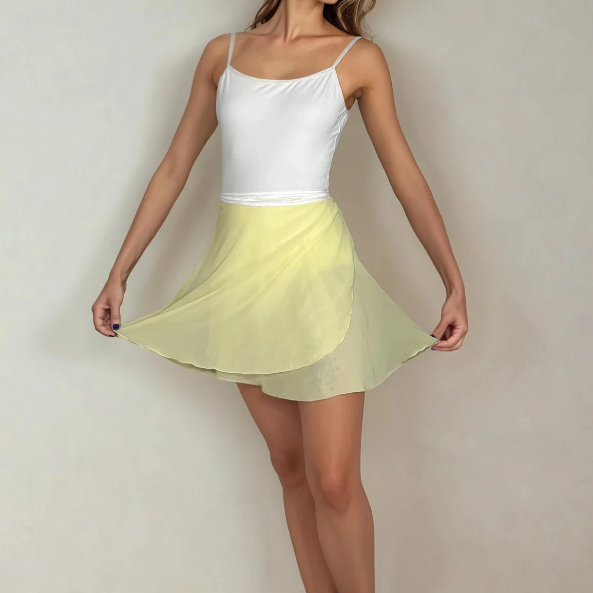Woman in a white top and yellow skirt standing against a plain wall.
