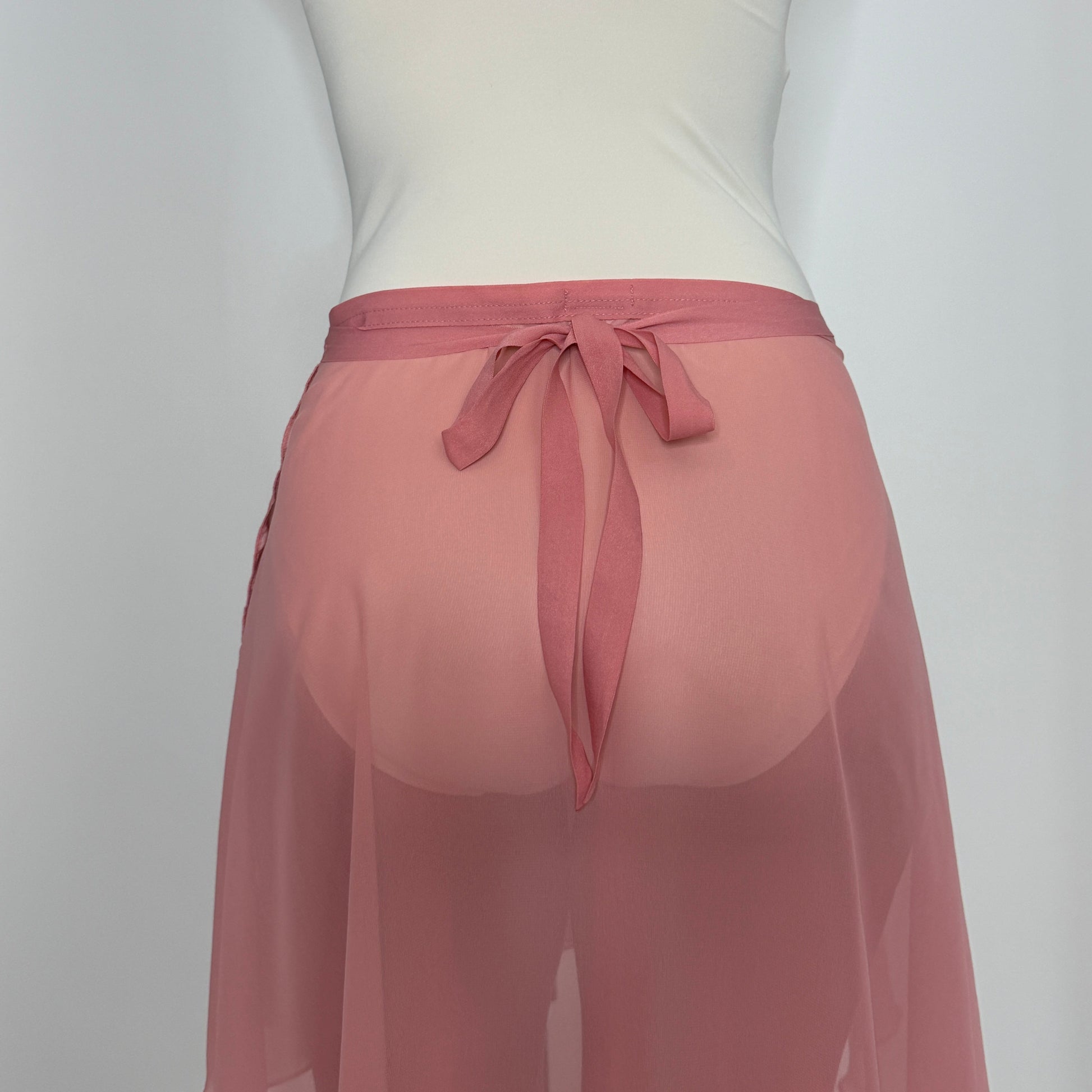 Person wearing a white tank top and pink sheer skirt on a plain background