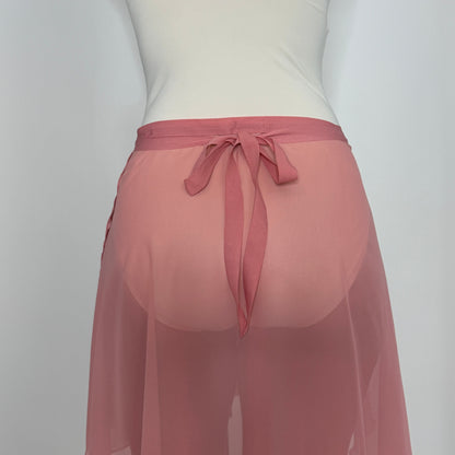 Person wearing a white tank top and pink sheer skirt on a plain background