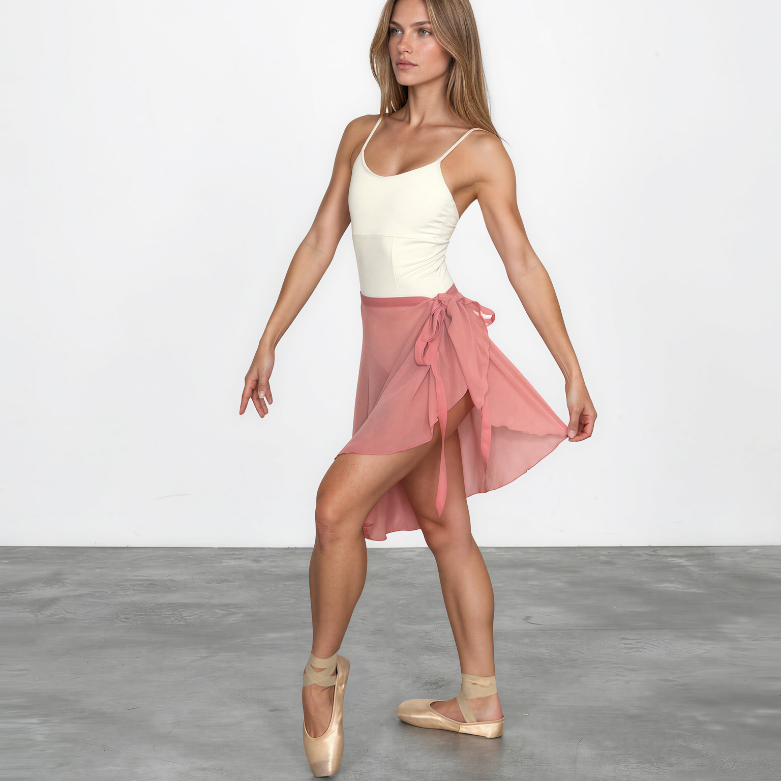 Woman in a white top and pink skirt standing on a gray floor with a white background