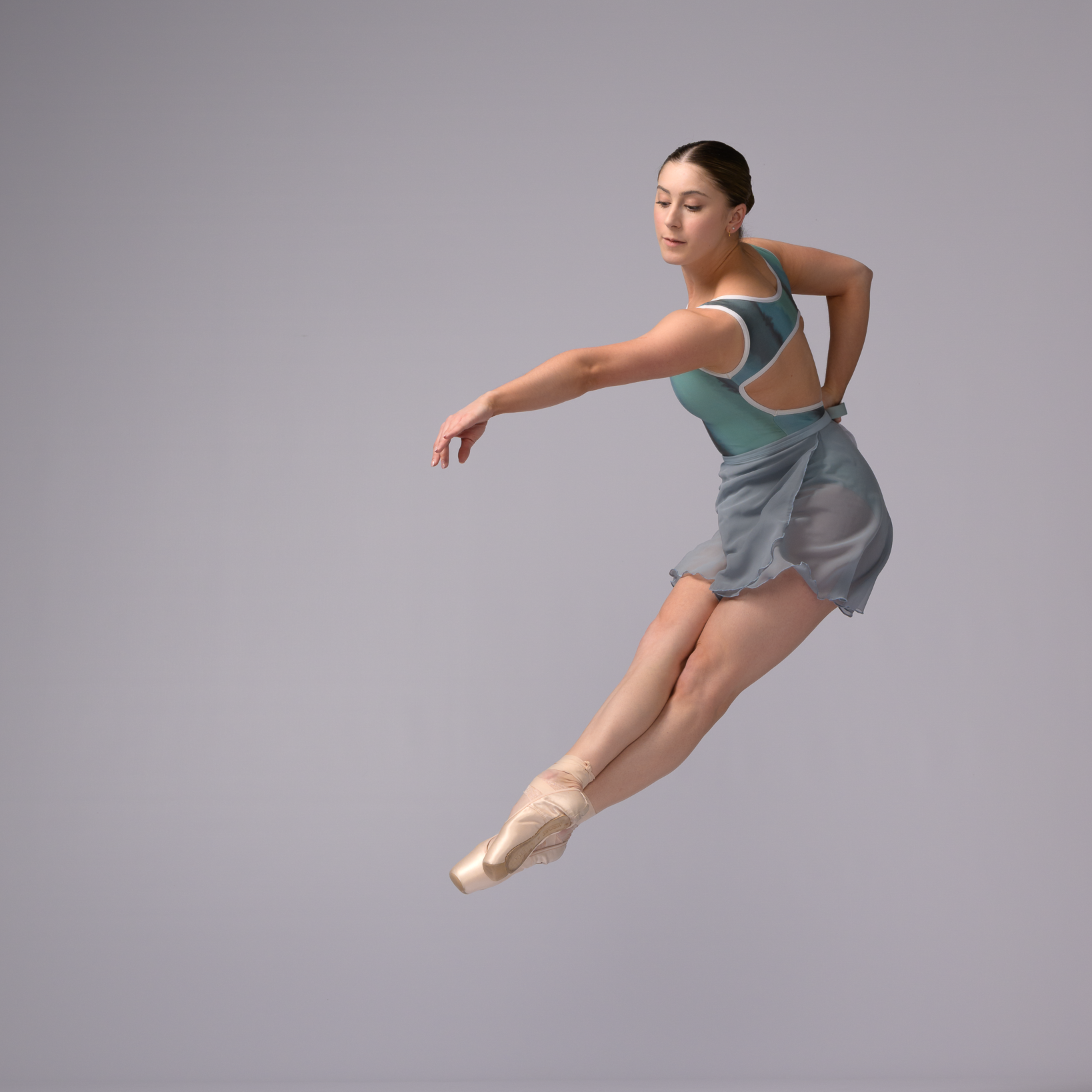 Ballerina in a blue leotard and skirt posing against a gray background