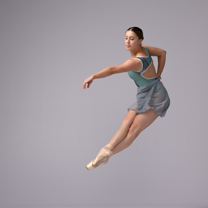 Ballerina in a blue leotard and skirt posing against a gray background