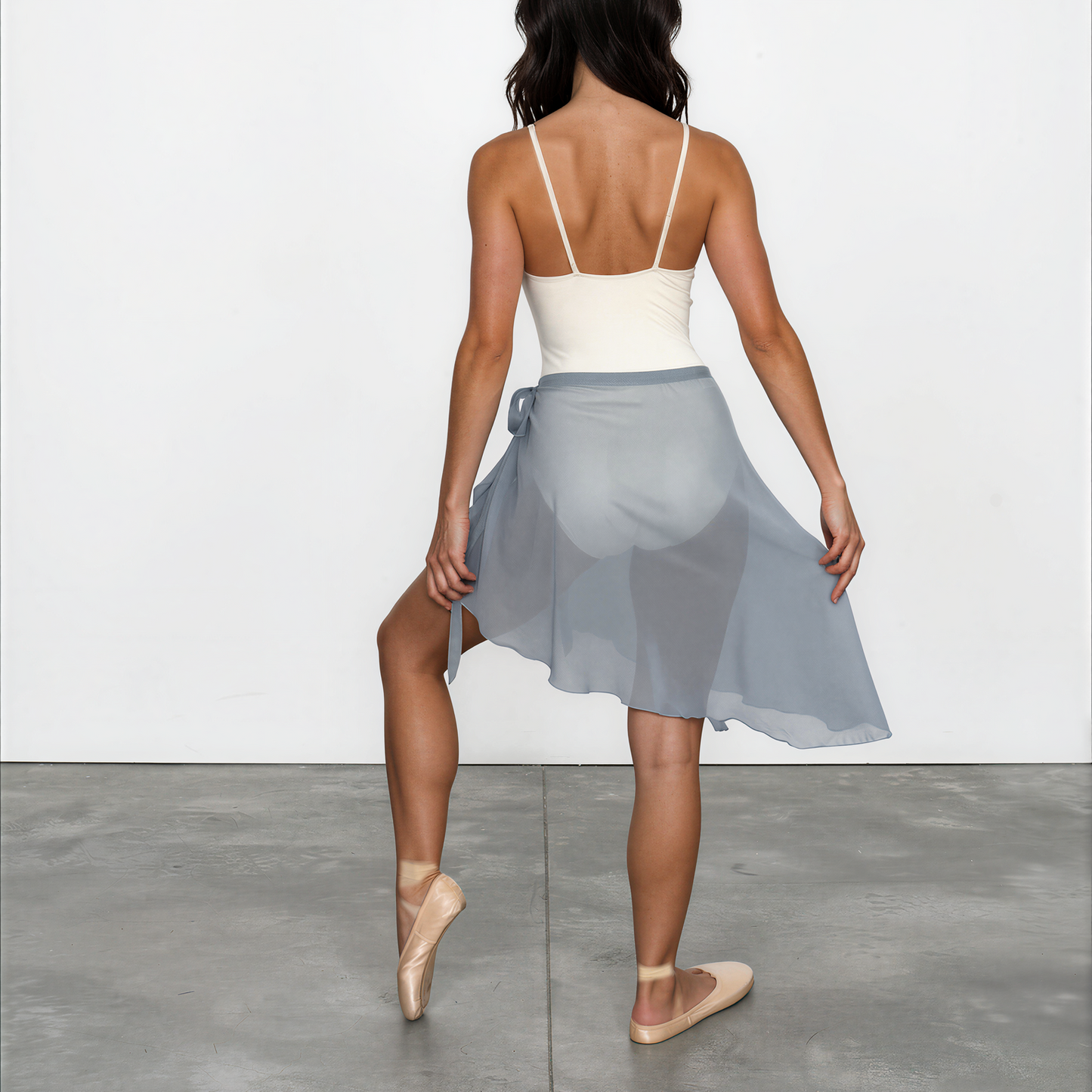 Woman wearing a white top and light blue skirt on a plain background
