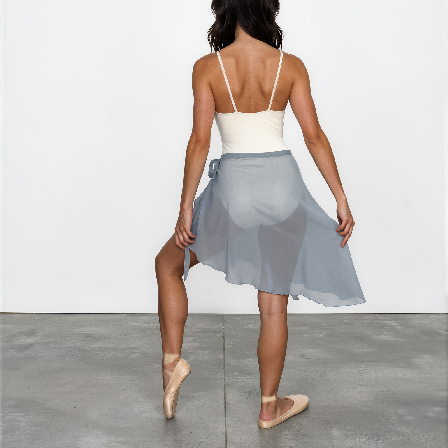 Woman wearing a white top and light blue skirt on a plain background