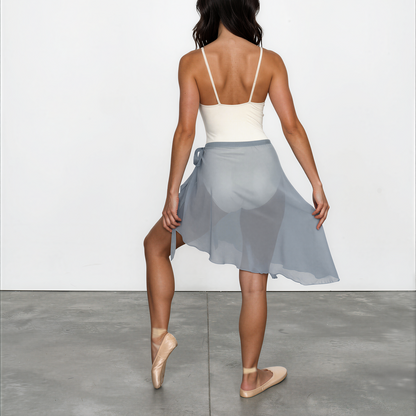 Woman wearing a white top and light blue skirt on a plain background