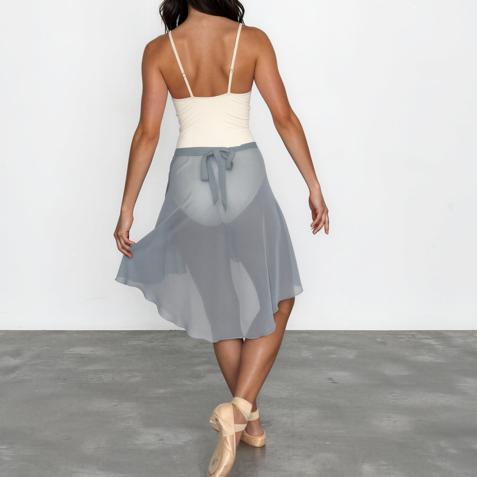 Woman wearing a white top and gray skirt on a plain background