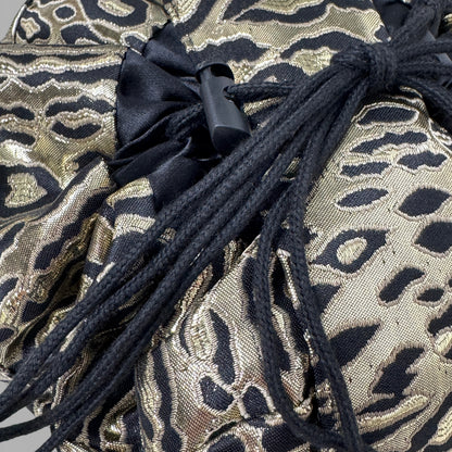 Gold and black patterned fabric with black drawstrings on a gray background