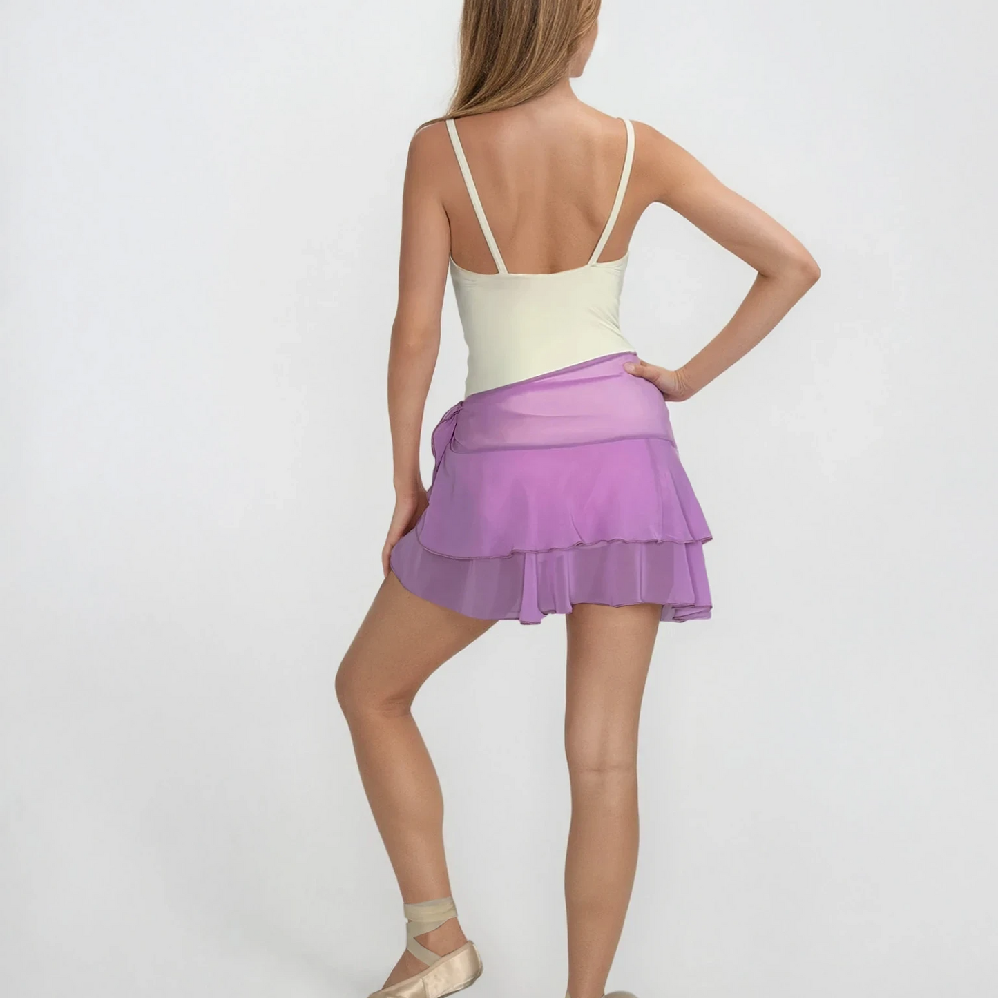 Woman wearing a white top and purple skirt on a plain background