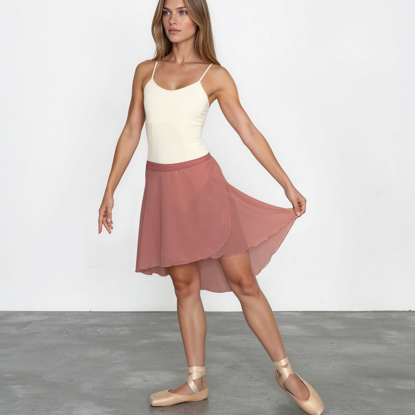 Woman wearing a white top and pink skirt on a plain background