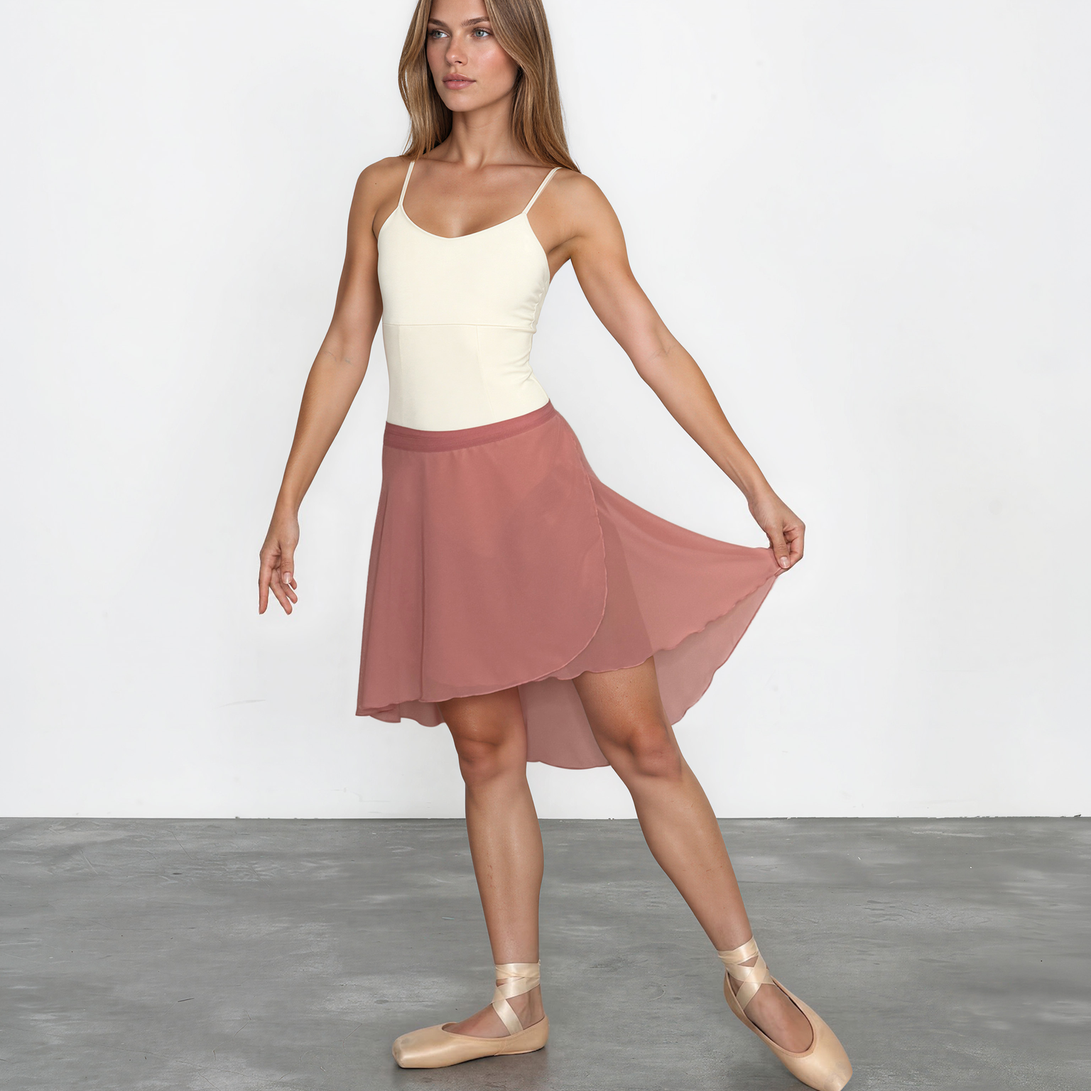 Woman wearing a white top and pink skirt on a plain background