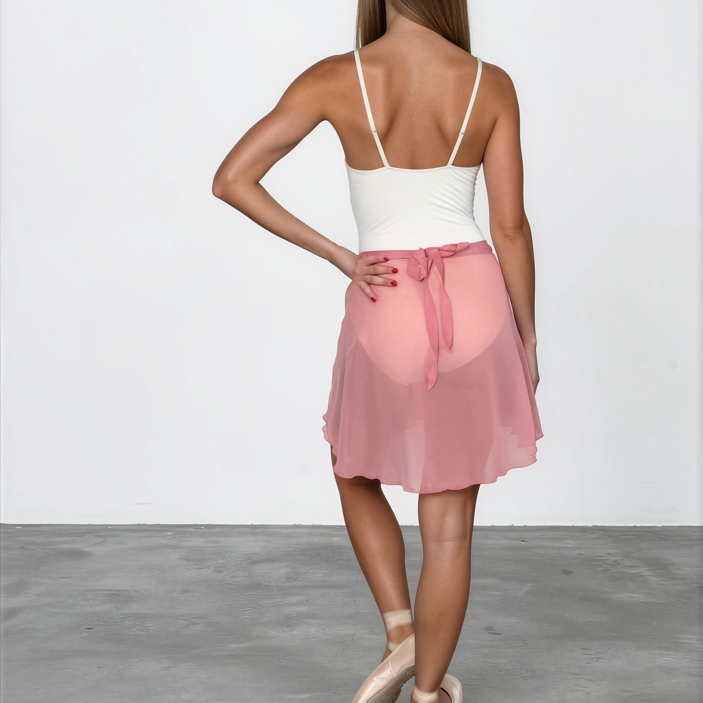 Woman wearing a white top and pink skirt on a plain background