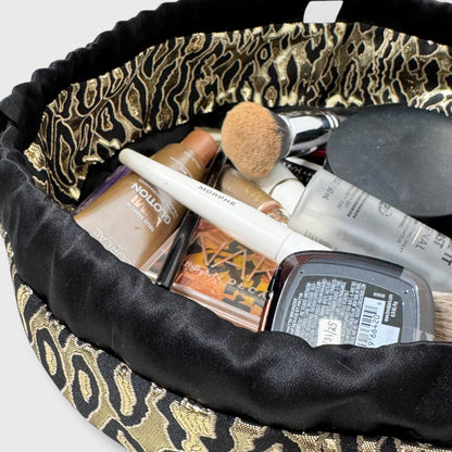 Makeup bag with leopard print trim containing various makeup items.