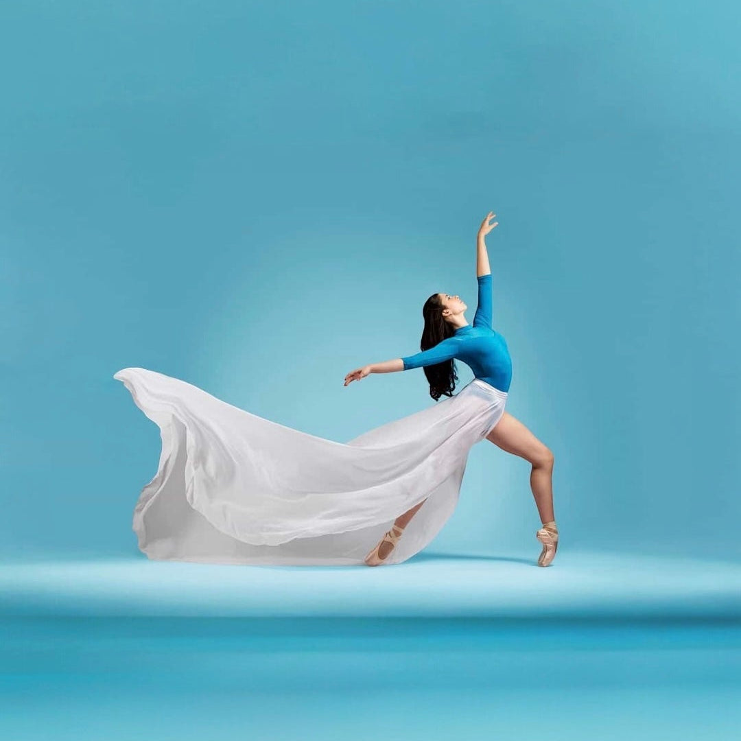 Dancer in a blue top and flowing white skirt against a gradient blue background