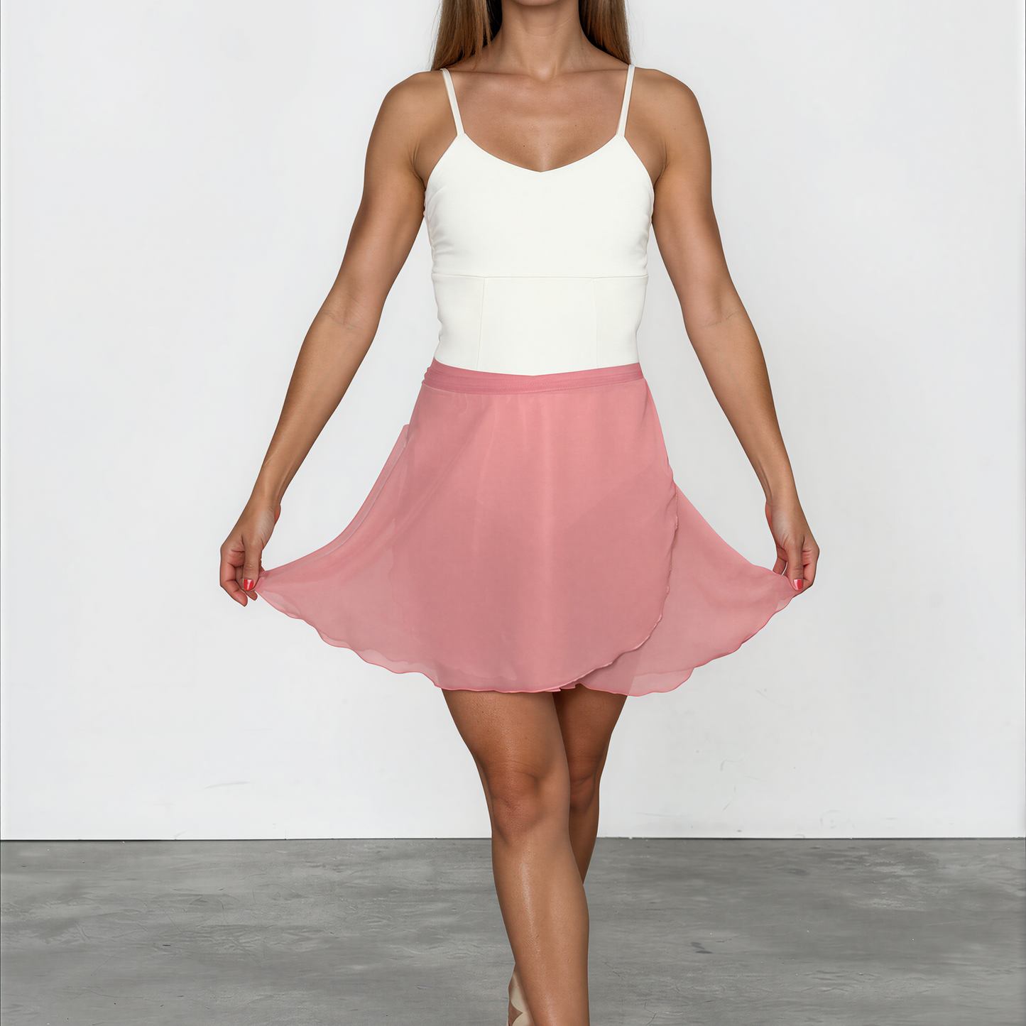 Woman wearing a white top and pink skirt on a plain background
