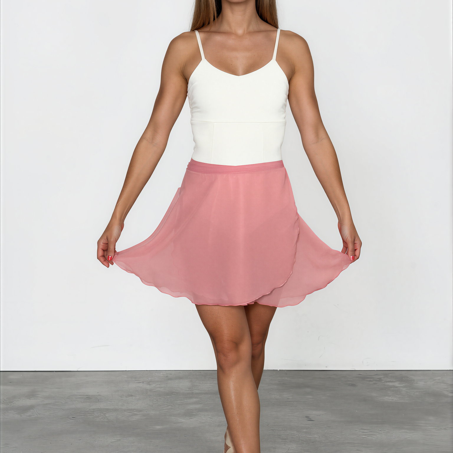 Woman wearing a white top and pink skirt on a plain background